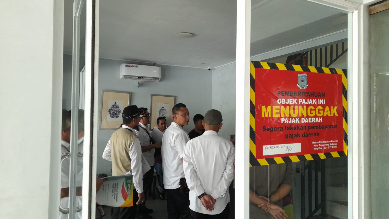 Petugas gabungan dari Pemkot Tangsel saat mendatangi hotel Reddoorz, nampak stiker warna merah bertuliskan pemberitahuan obyek pajak menunggak pajak terpasang di kaca pintu masuk hotel Reddoorz.(Dra)