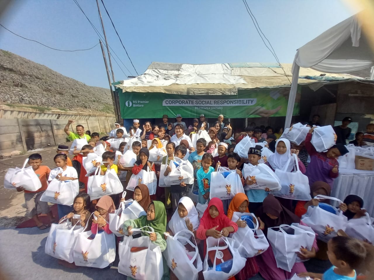 RS Premier Bintaro Beri Sepatu ke Anak-anak Pemulung di TPA Bantar Gebang Anak-anak di Bantar Gebang menerima bingkisan Sepatu dari RS Premier Bintaro. Foto : Dok. RS Premier Bintaro.