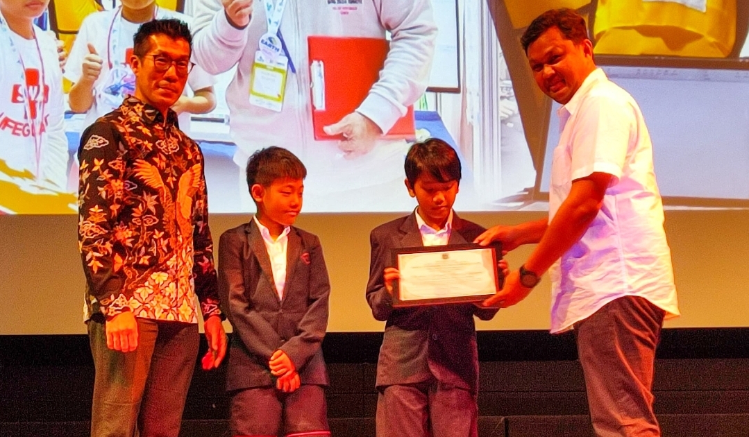 Kepala Dinas Pendidikan Kota Tangsel, Deden Deni, memberikan penghargaan kepada peraih juara 1 kategori Future Innovator Junior pada ajang World Robot Olympiad (WRO) Final Internasional 2024, Jumat (06/12/2024). (tangselpos.id/lim)