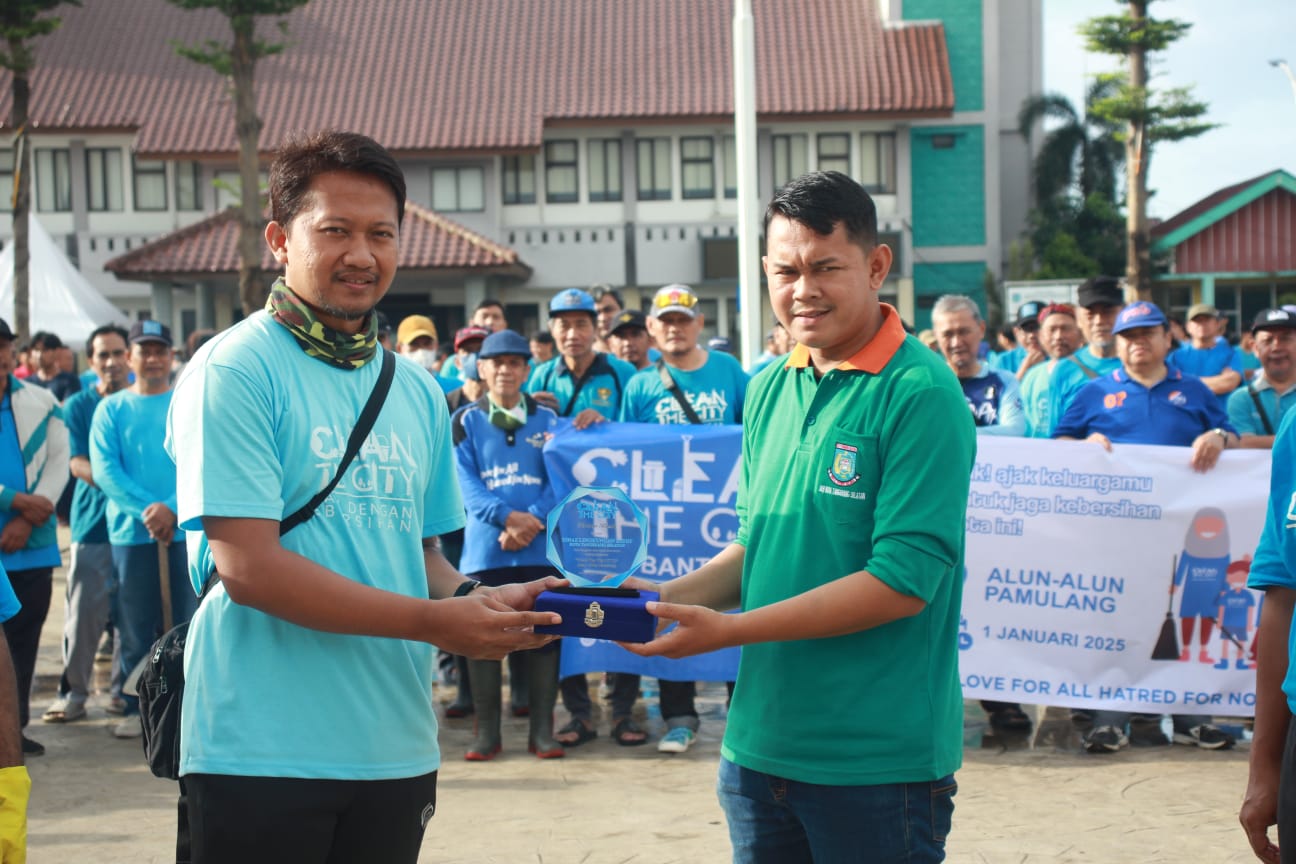 Clean the City, Jemaat Ahmadiyah Indonesia Bersama DLH Tangsel Bersih-bersih di Alun-alun Pamulang Ketua Pelaksana Clean the City di Alun-alun Pamulang, Anggi Arisandi (kiri) menyerahkan cenderamata ke perwakilan DLH Kota Tangsel. (tangselpos.id)