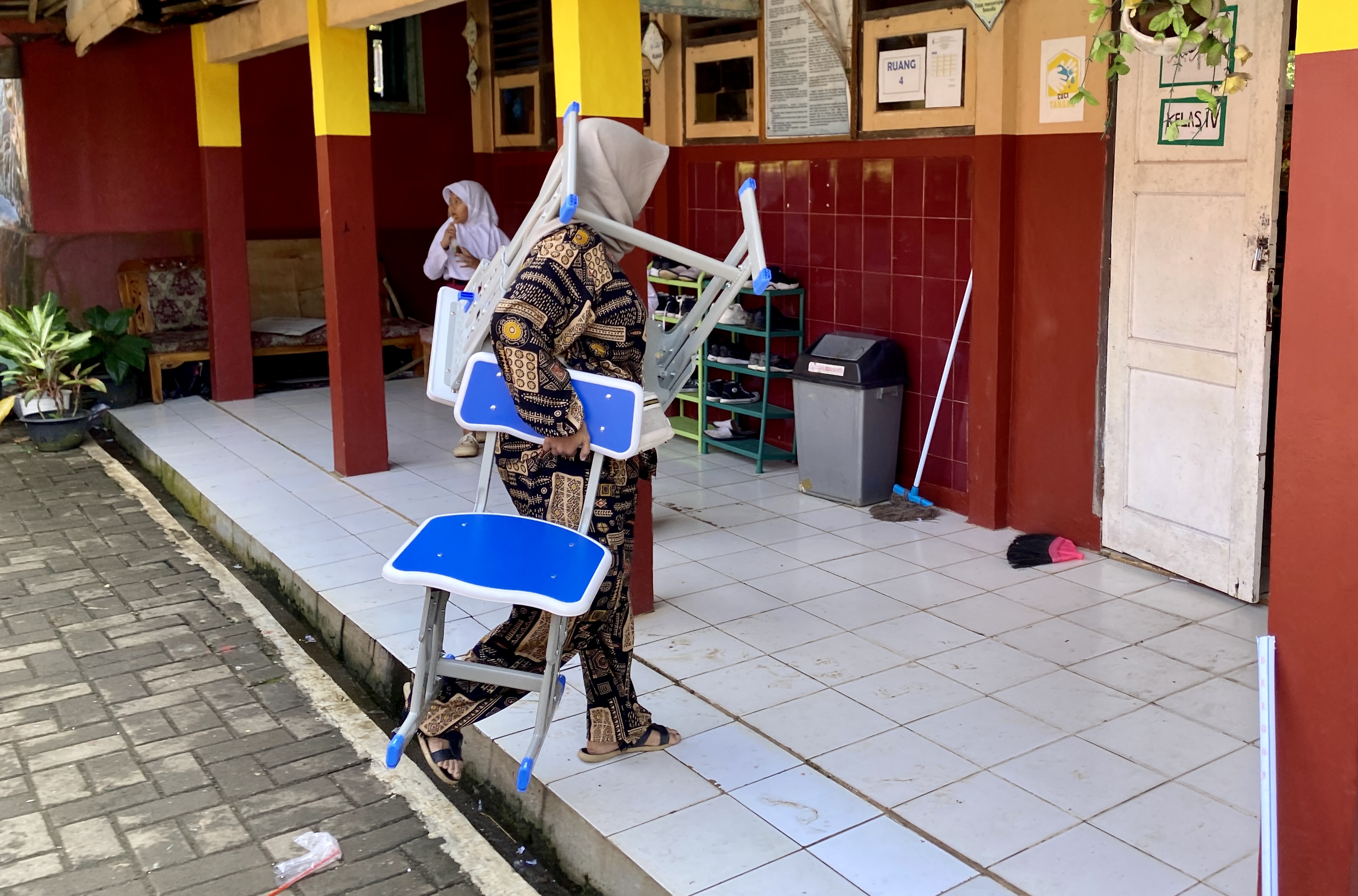 Kadisdik Bakal Evaluasi Perilaku Kepala SDN 2 Pasir Tangkil Wali murid Arta Grace Monica (35) sedang menggendong meja dan menjinjing kursi, untuk disimpan ke dalam kelas IV SDN 2 Pasir Tangkil, beberapa waktu lalu.