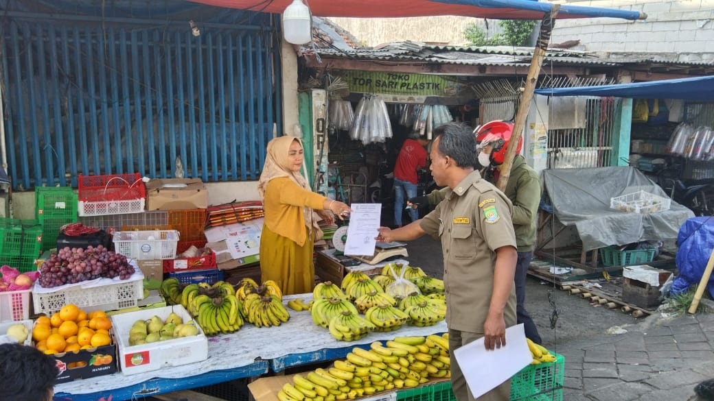 Pemkot Tangerang Ajak PKL Pasar Anyar Berjualan Dengan Tertib Petugas Tramtib Kecamatan Tangerang saat membagikan surat edaran kepada PKL.