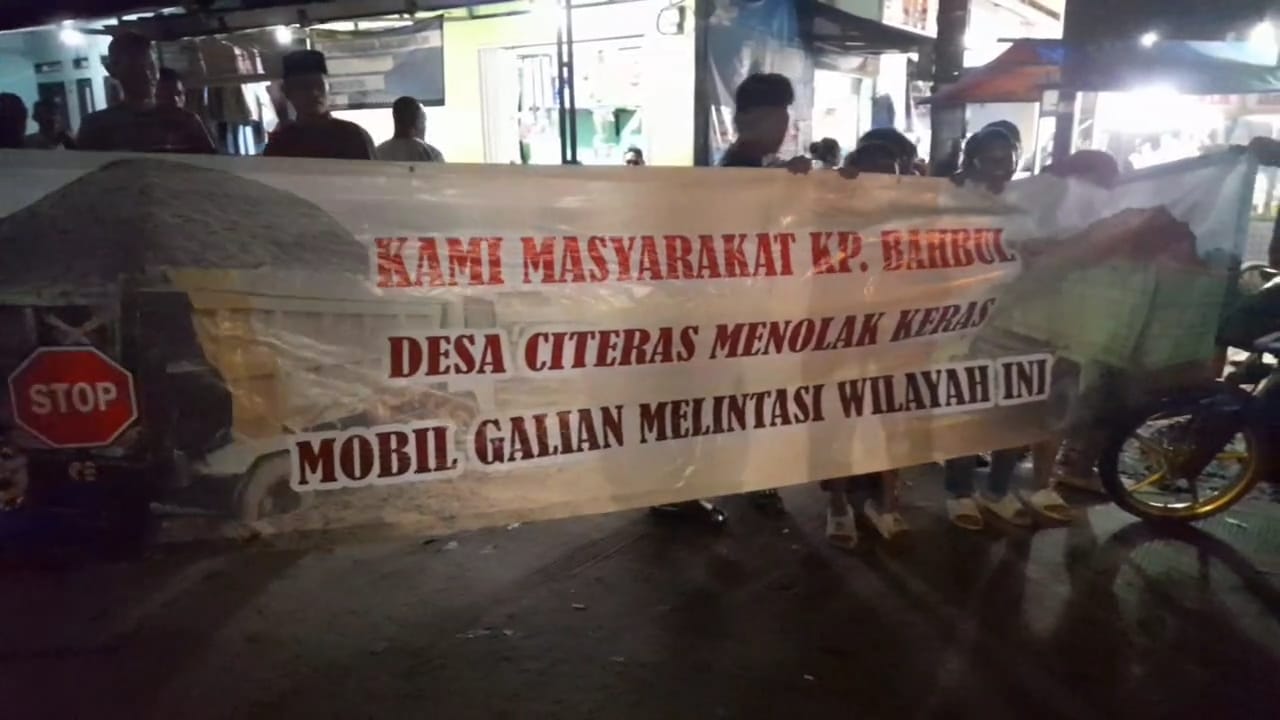 Warga Tolak Pengalihan Jalur Truk Tonase Warga sedang membentangkan spanduk penolakan pengalihan jalur, di ruas jalan Cijalur-Citeras, pada Rabu, (18/6) malam.