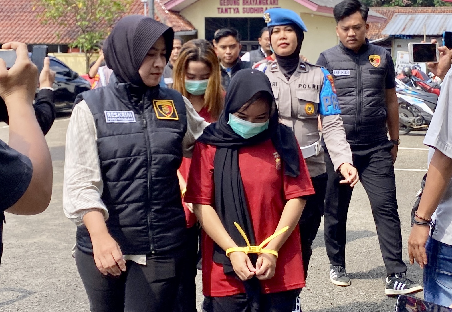 Jajaran Satreskrim Polres Pandeglang sedang menggiring para tersangka kasus TPPO dengan tangan terikat kabel tis dan menggunakan baju tahanan, saat hendak melakukan ekspose di halaman Mapolres Pandeglang, Rabu (30/7).