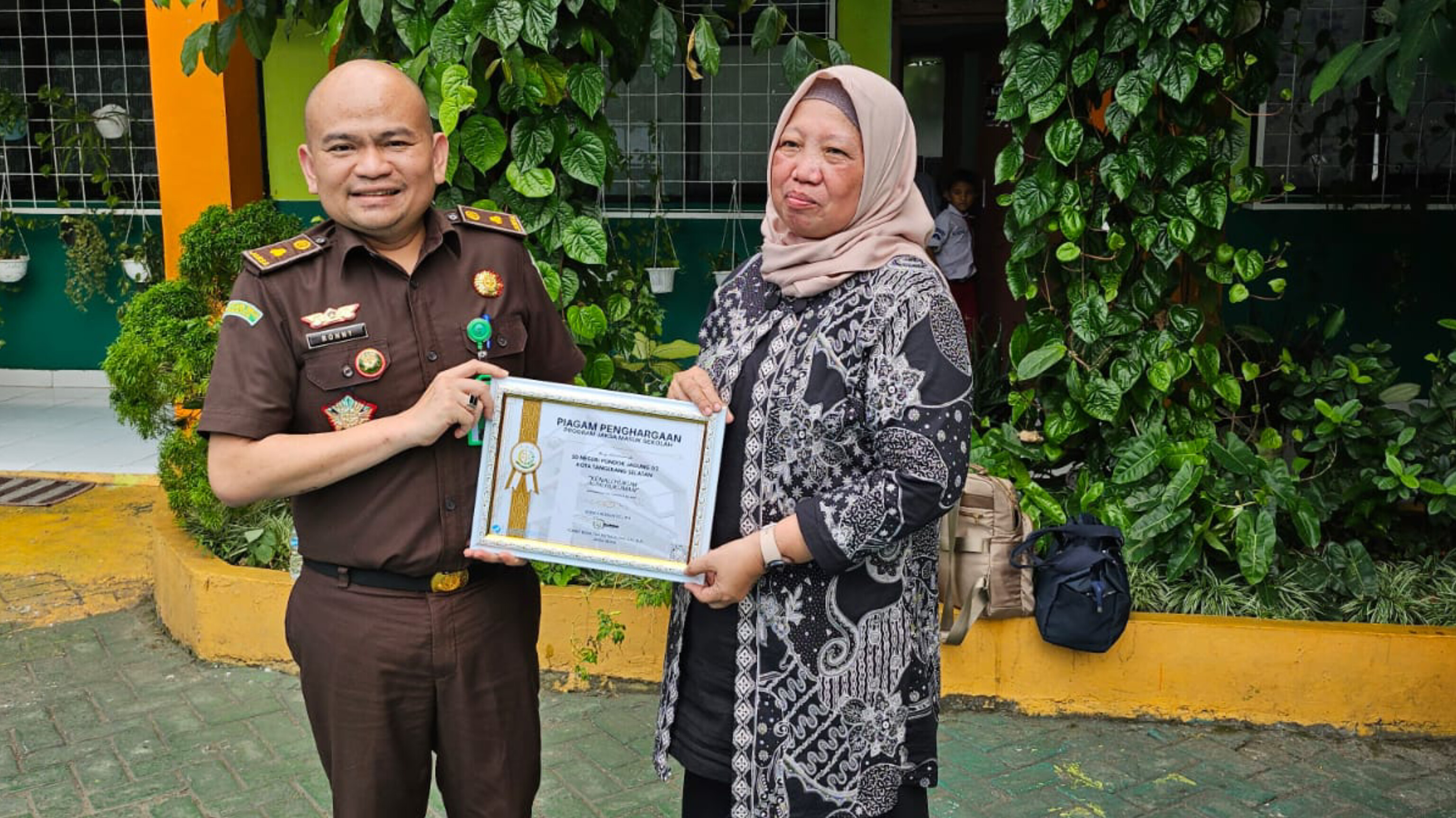 Kepala Seksi Intelijen Kejaksaan Negeri Kota Tangerang Selatan, Tonny, menyerahkan piagam penghargaan kepada Kepala SDN Pondok Jagung 02, Sawiah, sebagai bentuk apresiasi dalam kegiatan “Jaksa Masuk Sekolah” di Tangerang Selatan, Kamis (31/7/2025). (Ist)