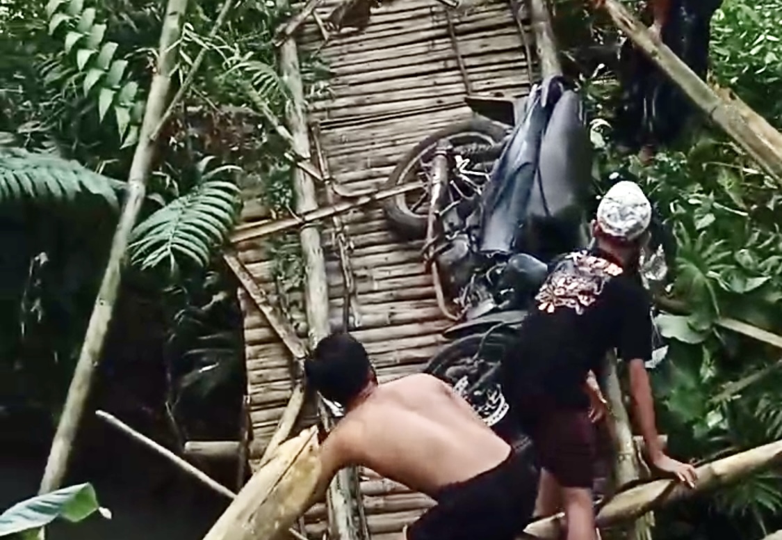 Para santri sedang menyelamatkan diri dan kendaraannya yang terperosok di jembatan bambu yang ambruk, di Kampung Ciliang, Kelurahan Kadumerak, Kecamatan Karangtanjung, Kabupaten Pandeglang, Senin (30/6).