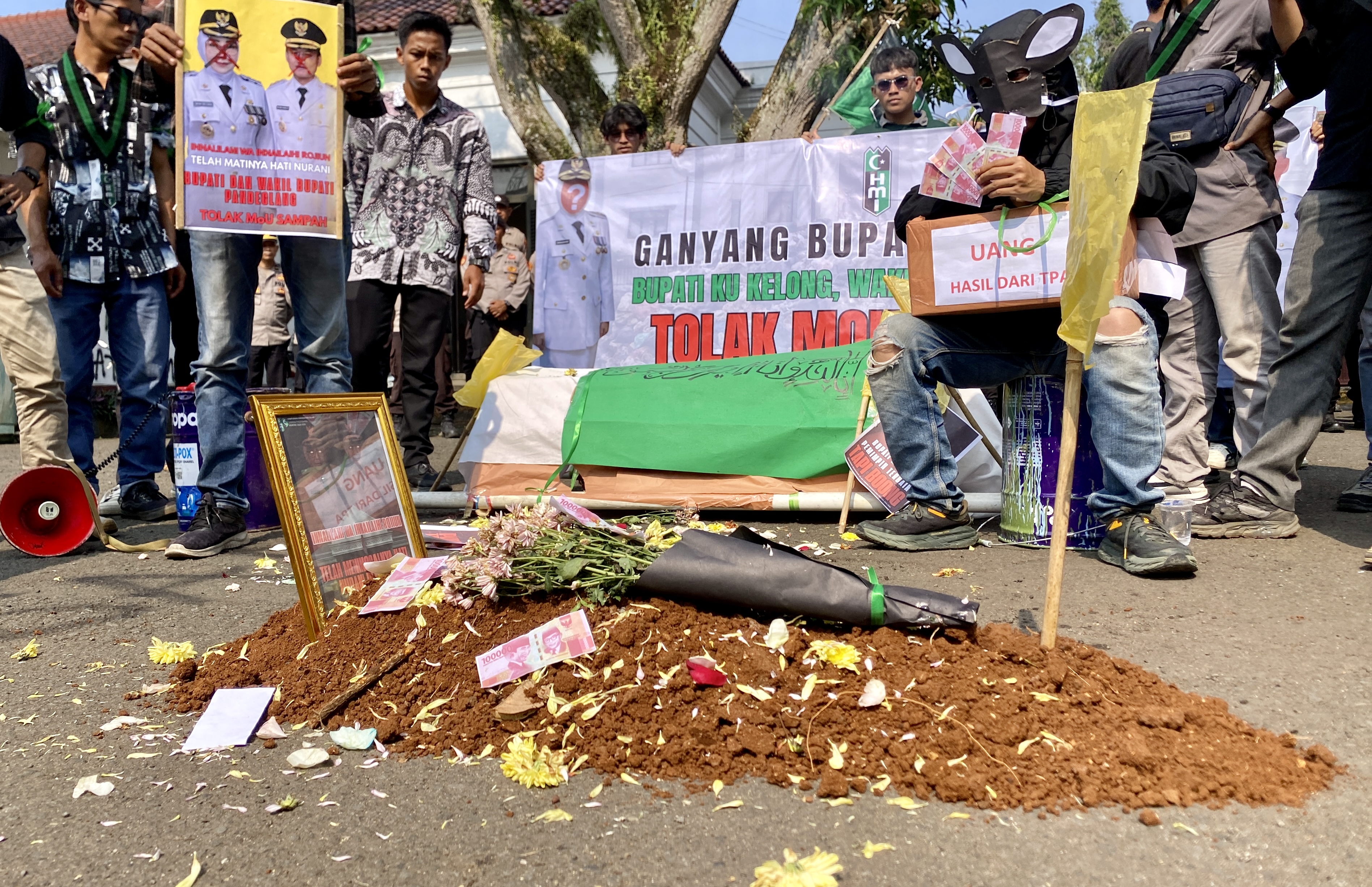 Dewi-Iing Kerap Menghilang Saat Didemo Soal Sampah Aktivis HMI Cabang Pandeglang sedang melakukan teatrikal dengan membuat kuburan yang ditaburi bunga, uang dan diberi foto, serta ada manusia berwajah tikus, saat melakukan aksi unjuk rasa di Pendopo Bupati Pandeglang, Selasa (26/8).