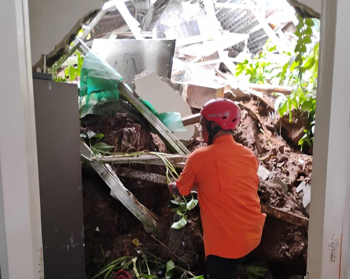 Hujan Deras Picu Tebing Longsor, Tembok Dapur Warga Villa Pamulang Jebol Petugas BPBD Tangsel saat mengevakuasi dapur rumah warga di Villa Pamulang, Kelurahan Bakti Jaya, yang jebol akibat longsor, Kamis (23/10). (Dok. BPBD Tangsel)
