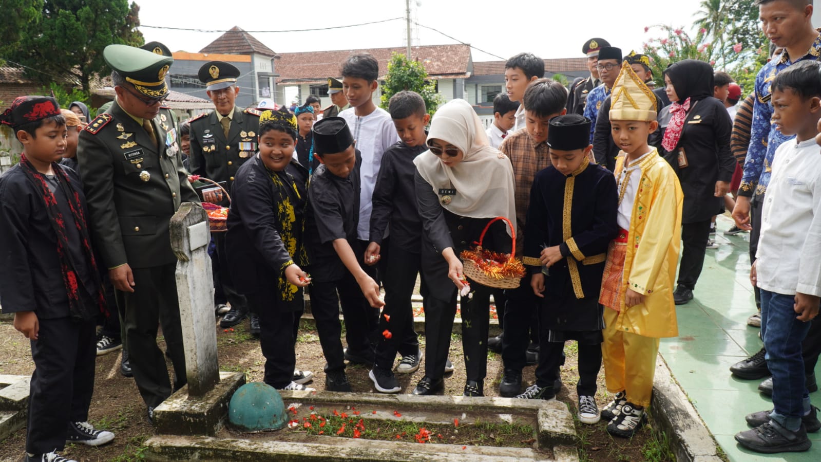Bupati Pandeglang, Raden Dewi Setiani, ditemani siswa sekolah dasar menabur bunga di Taman Makam Pahlawan (TMP) Cihaseum, Pandeglang, Senin (10/11/2025).(Istimewa)