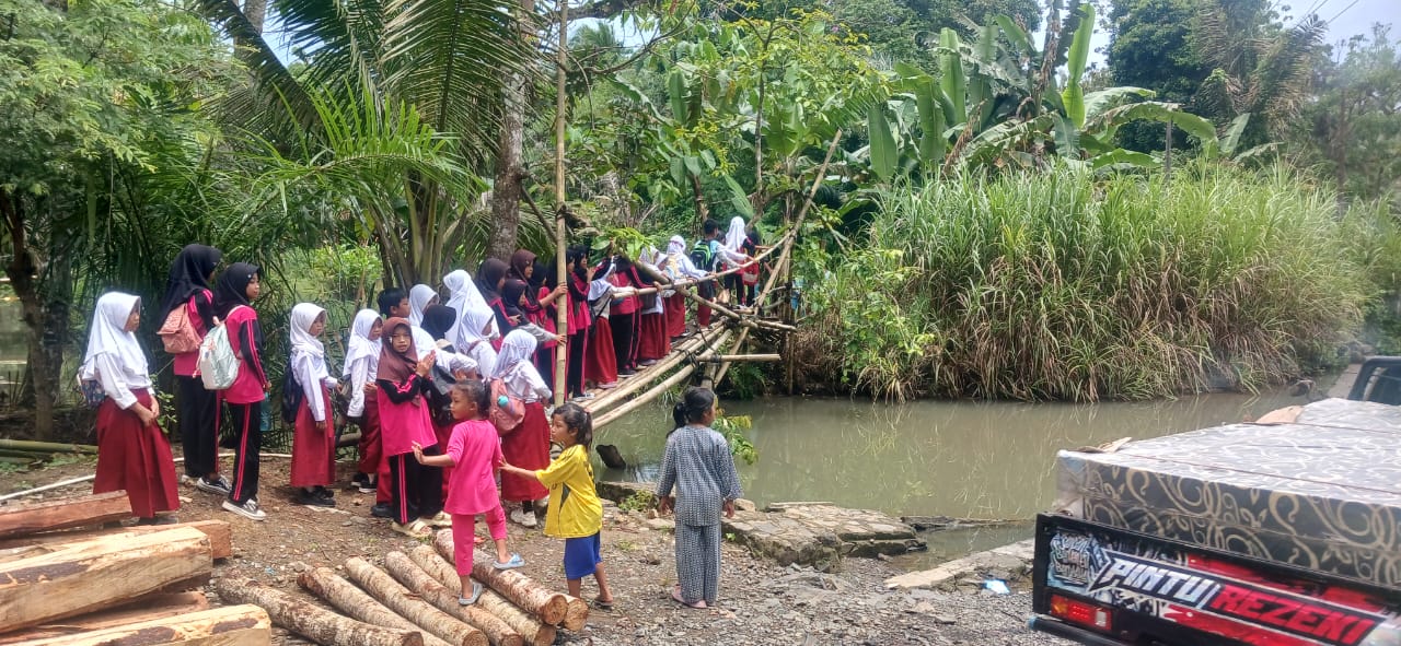 Sejumlah murid SDN Cikadongdong 2 di Kecamatan Cikeusik, Kabupaten Pandeglang, Rabu (12/11/2025) menyeberangi jembatan bambu di atas sungai dangkal.(Istimewa)