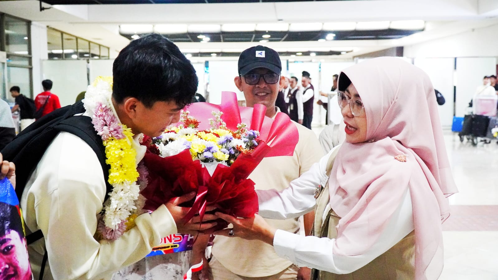 Bupati Pandeglang, Raden Dewi Setiani memberikan bunga kepada M. Ibnu Alan, di Bandara Soetta, Tangerang, Selasa (30/12/2025) malam. Ibnu merupakan atlet futsal yang berhasil menjadi juara AFF Cup Futsal U-16 2025 di Thailand.(Istimewa)