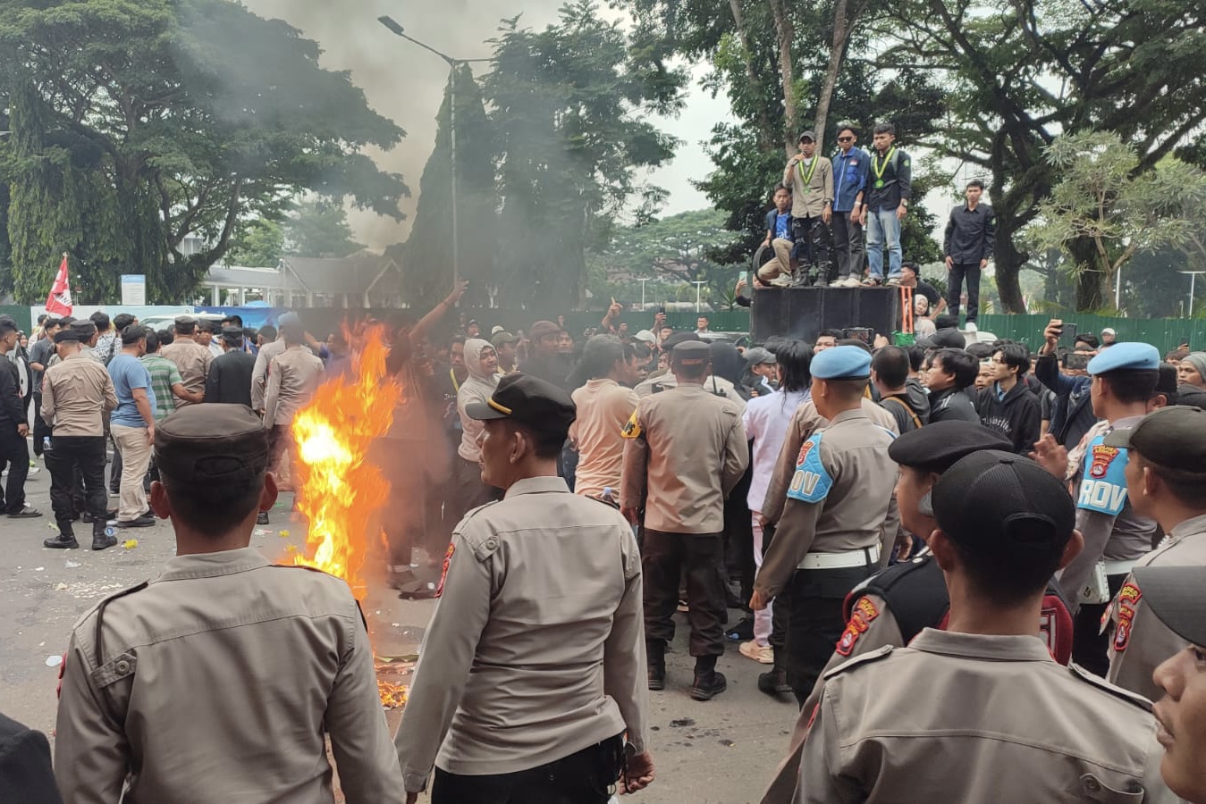 Ratusan mahasiswa sedang melakukan unjuk rasa dengan melakukan orasi, membentangkan spanduk dan poster kecaman, serta membakar ban bekas, di depan Kantor Bupati Kabupaten Lebak.
