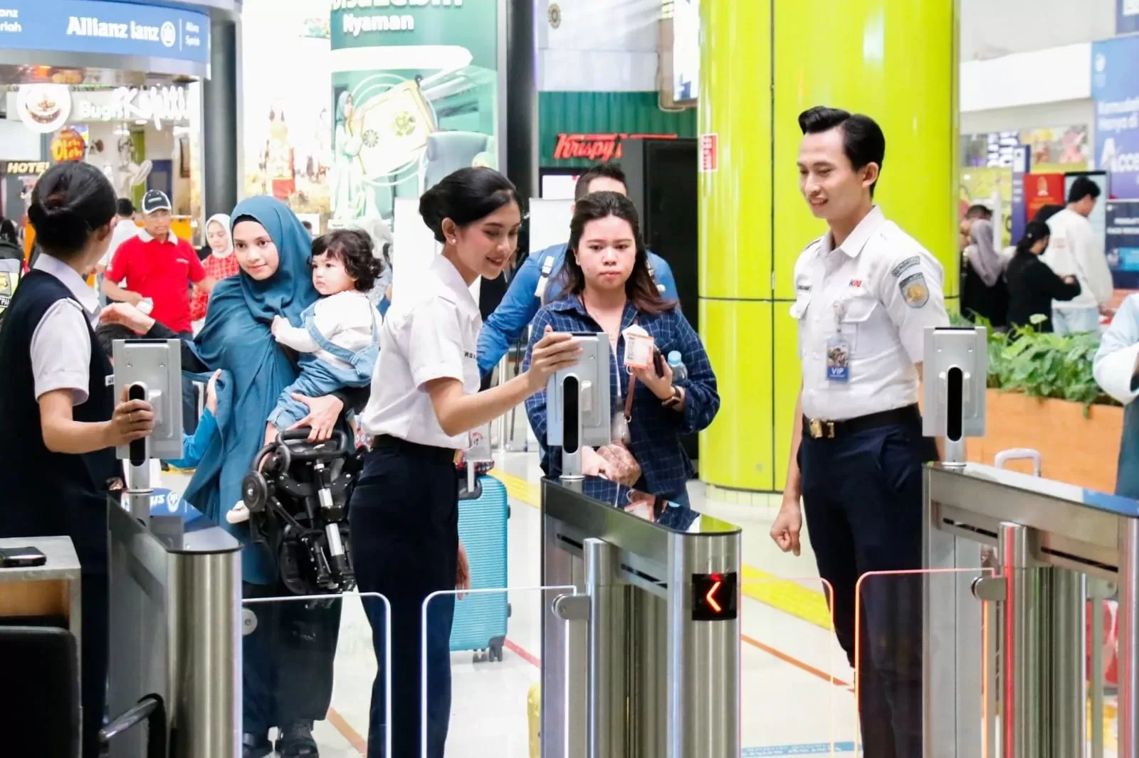 Calon penumpang kereta api di Stasiun Gambir dipandu petugas untuk menggunakan face recognition ketika hendak chek in. Foto : Ist