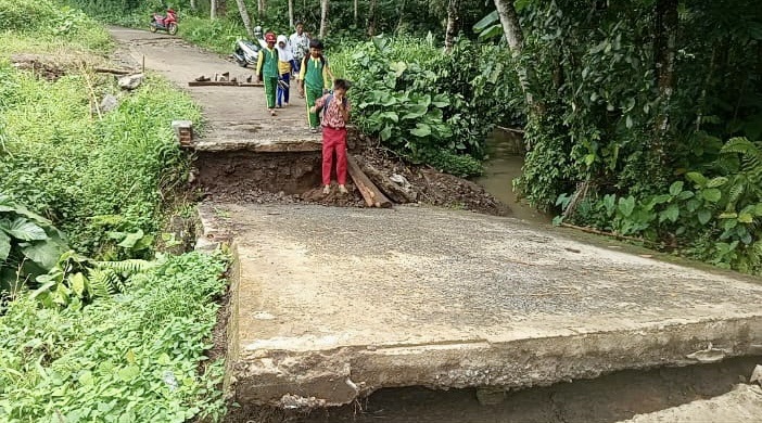 MELINTASI JEMBATAN AMBRUK. Anak-anak yang hendak bersekolah ke SDN Jiput 2, tengah melintasi jembatan Cikoter di Kampung Malangnengah, Desa Jiput, Kecamatan Jiput, Kabupaten Pandeglang, yang kondisinya ambruk dan membahayakan, Kamis (26/2).
