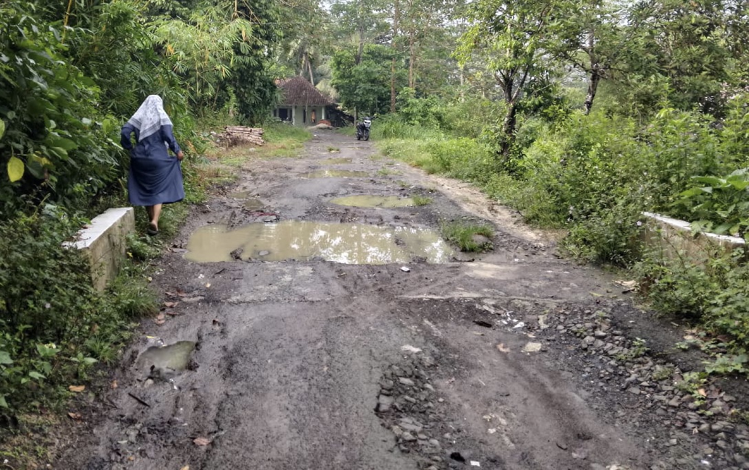 Salah seorang warga terlihat berhati-hati saat menghindari kondisi jalan rusak parah yang tergenang air, di Kampung Suminta, Desa Sukadaya, Kecamatan Cikulur, Kabupaten Lebak, Minggu (19/4).