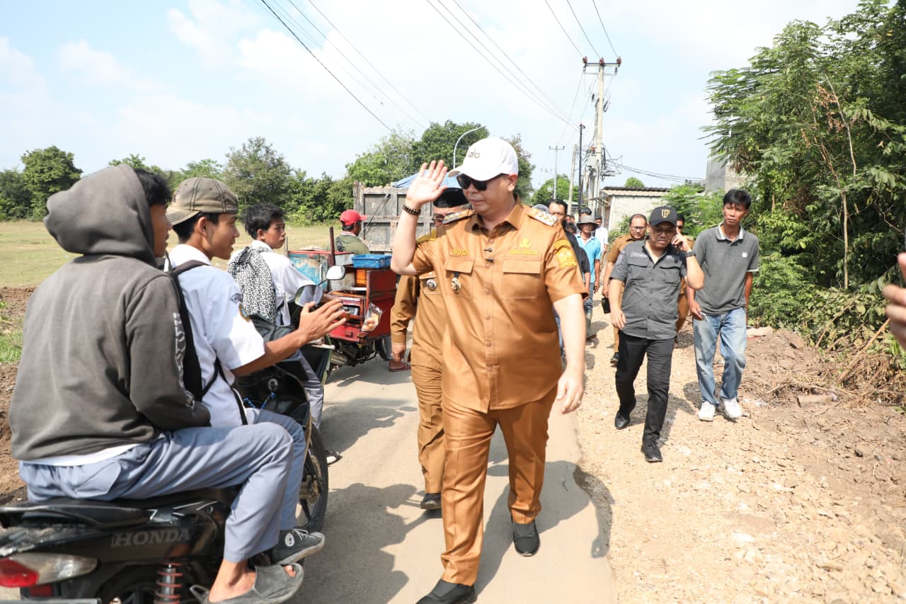Wali Kota Serang, Budi Rustandi, Senin (20/4/2026) menyapa siswa yang tengah melintas di sela-sela monitoring betonisasi jalan di Kecamatan Kasemen.(Istimewa)