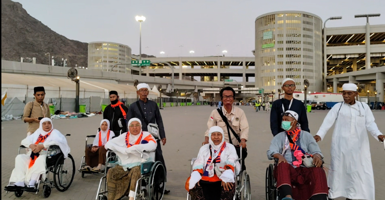 Petugas Haji M Rusmadi (no 3 dari kanan) saat membantu jamaah Haji mendorong kursi roda. Foto :  Ist