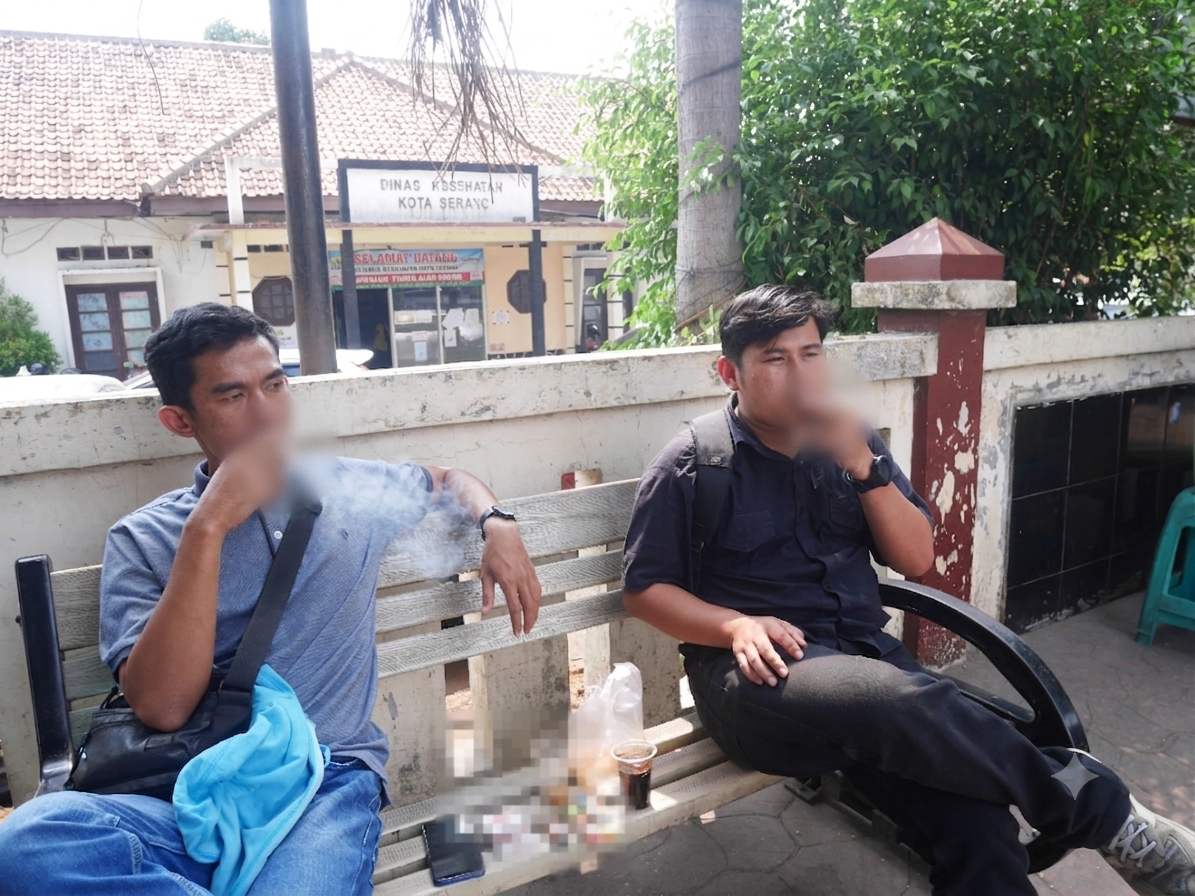 Dua orang warga nampak merokok di depan Kantor Dinkes Serang di Jalan Jendral Ahmad Yani, belum lama ini.(Ari Supriadi-tangselpos.id)