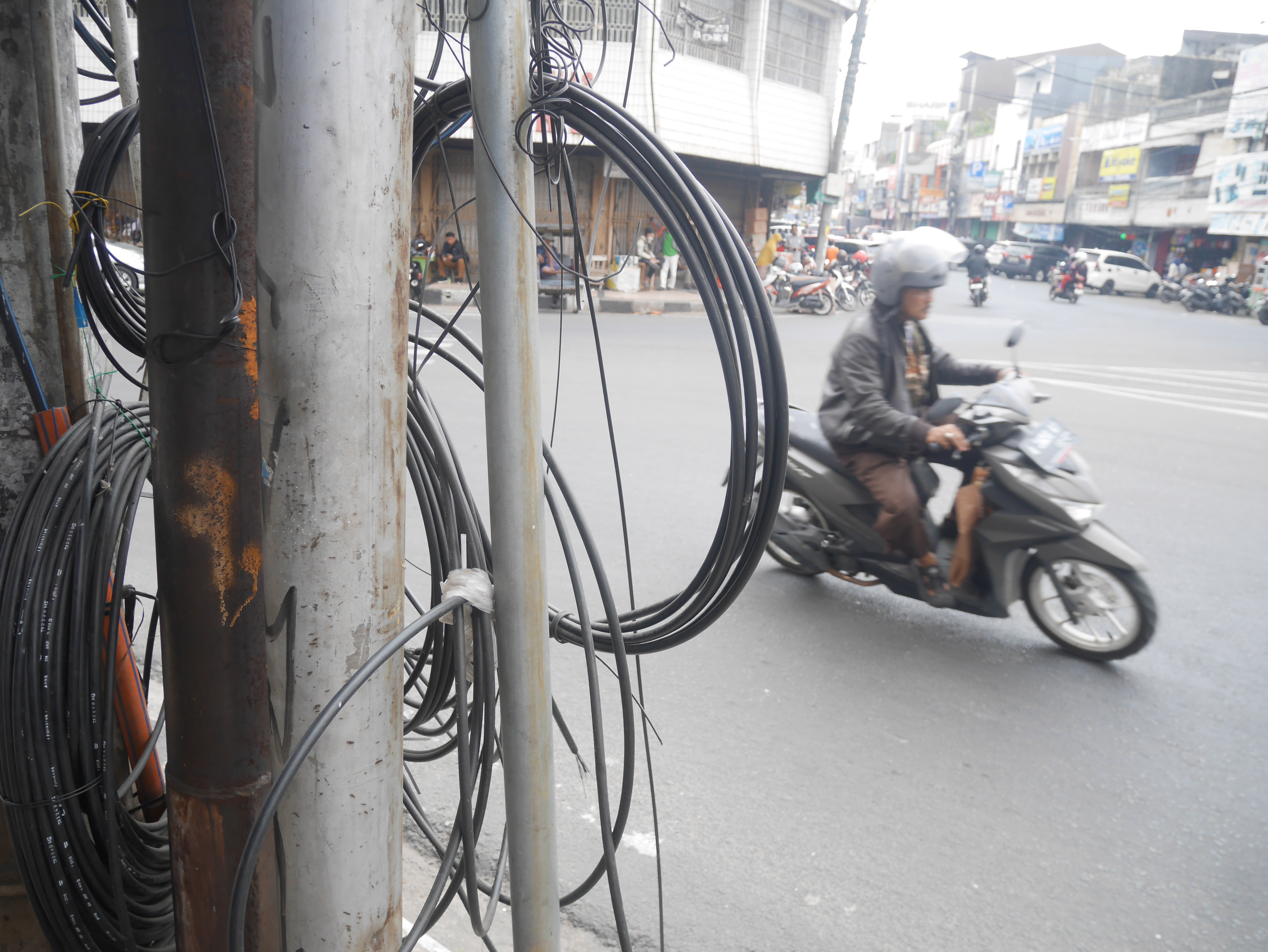 Kabel jaringan internet nampak semraut di tiang listrik dengan latar pengendara sepeda motor yang melintas di Jalan Mayor Safei, Kota Serang, Selasa (28/7/2026).(Ari Supriadi-tangselpos.id)