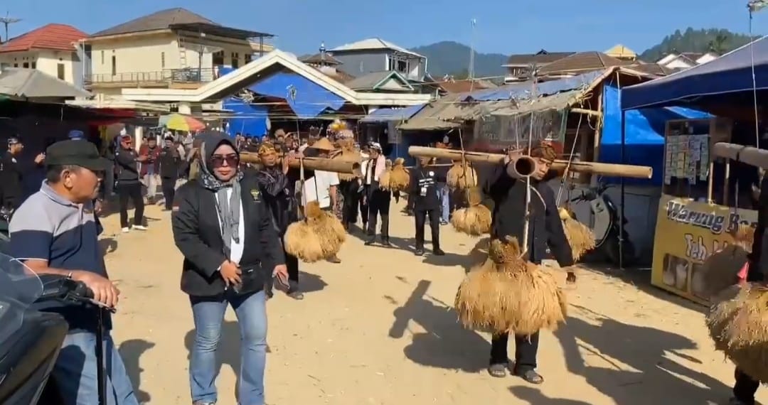 MEMIKUL PADI. Masyarakat sedang memikul puluhan ikat padi menggunakan rengkong, alat angkut tradisional berbahan bambu yang menghasilkan bunyi khas saat digerakkan, saat kirab budaya di acara Seren Taun, Senin (13/7). (DOK. WARGA)
