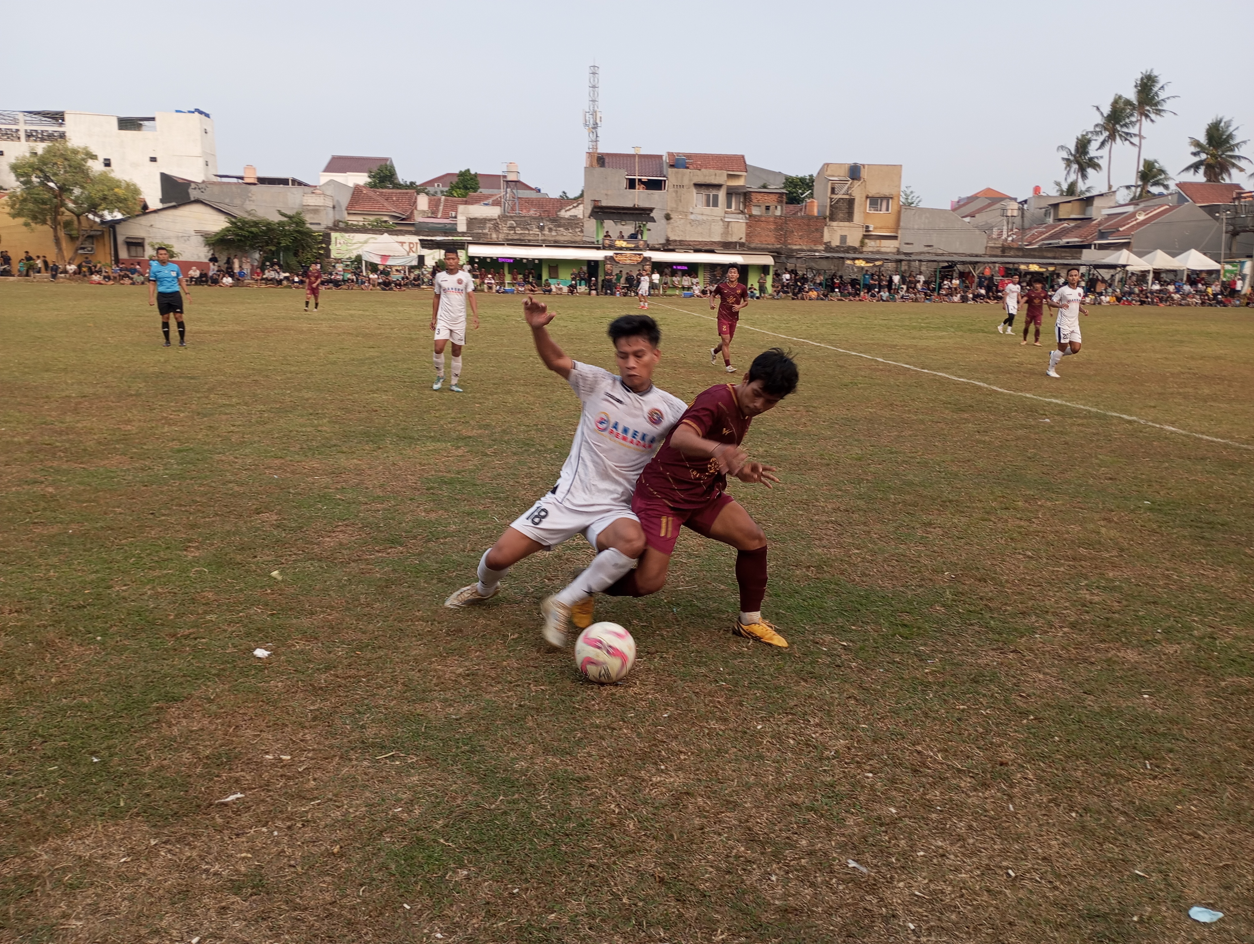 Penyerang Pancaran Muda FC, Karim (putih) berduel dengan pemain Justice Law Soccer FC pada laga Minggu (18/10/2026) sore.(red/tangselpos.id).