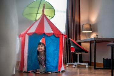 Nampak seorang anak sedang bermain di dalam tenda yg berada di kamar hotel. (Ist)