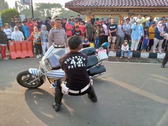 Anggota polisi lalu lintas memperagakan cara mengangkat moge yang terjatuh, dalam rangkaian peringatan HUT ke-76 Bhayangkara di Alun-alun Pandeglang, Minggu (3/7/2022).(Ari Supriadi/Tangsel Pos)