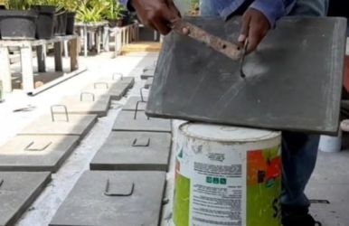 Seorang pekerja sedang mengerjakan penutup got dari beton. Foto : Istimewa