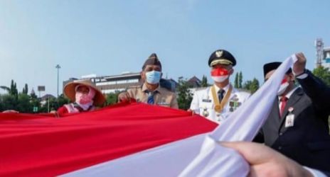 Gubernur Jawa Tengah Ganjar Pranowo bersama Serikat Buruh Migran membentangkan bendera sepanjang 22 meter di lapangan Pancasila, Semarang. (Ist)