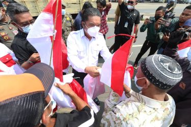 Pj Gubernur Banten Al Muktabar membagikan bendera merah putih kepada perwakilan pelajar, santri serta organisasi kemasyarakatan. (Dok. Humas Pemprov)