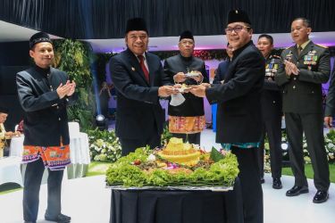 Pj Gubernur Banten Al Muktabar menyerahkan potongan tumpeng kepada Ketua DPRD Kota Tangsel Abdul Rasyid. (Foto : Humas Pemprov)