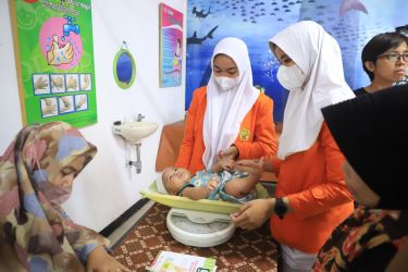 Seorang bayi sedang ditimbang berat badannya saat mengikuti layanan imunisasi yang digelar serentak di seluruh puskemas melalui posyandu yang tersebar di Kota Tangerang.