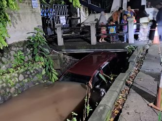 Satu unit mobil tampak terperosok di sebuah sungai di pondopk Cabe, Kecamatan Pamulang, Kecelakaan itu akibat pengemudi alami tergelincir.(dra)