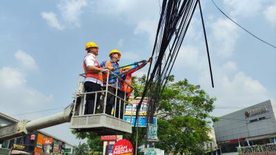 PUTUSKAN KABEL: Petugas Dinas PUPR saat memutus kabel fiber optik di Jalan Raden Fatah, kemarin. ISTIMEWA